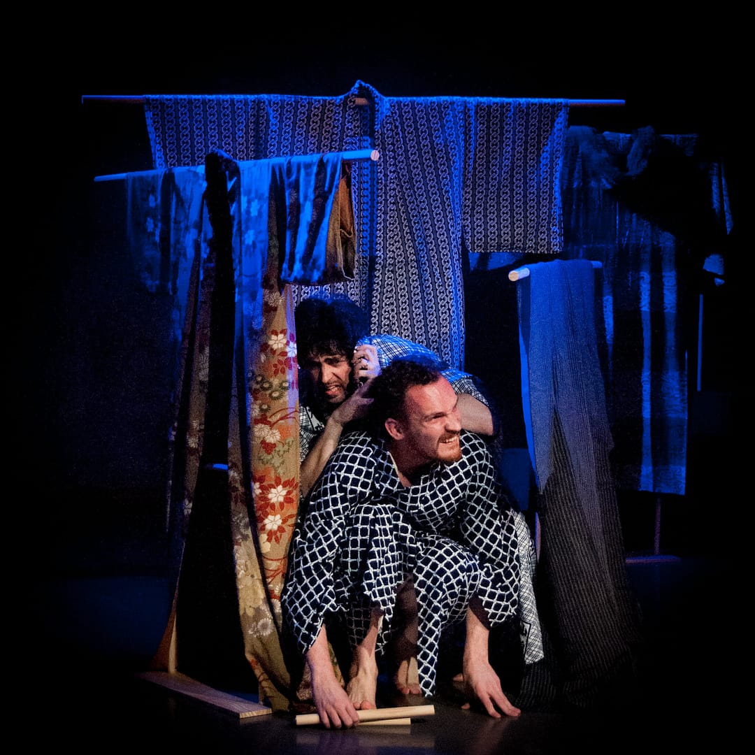 Naritsune (Andrew Woolner) and Yasuyori (Graig Russell) hide in an improvised shelter as the rain falls on Kikai-ga-shima.